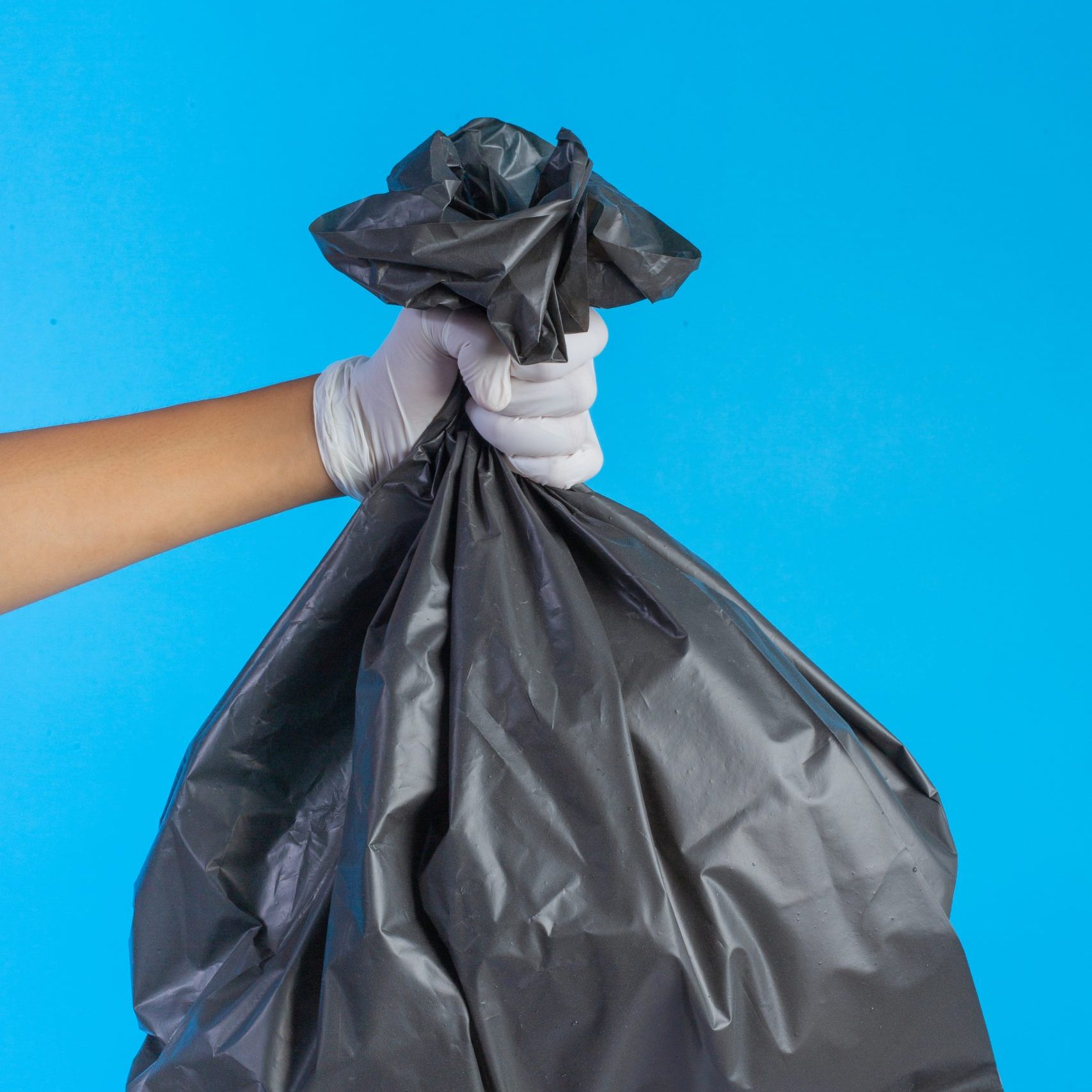 The male hand holding a garbage bag and a blue background.